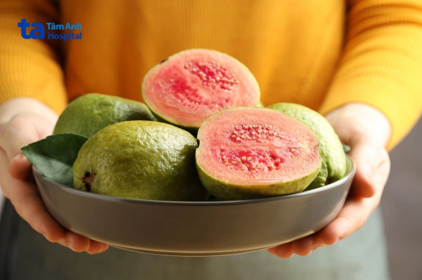 Bát ổi hồng đào tươi ngon được cầm trên tay, giàu vitamin C tốt cho bà bầu